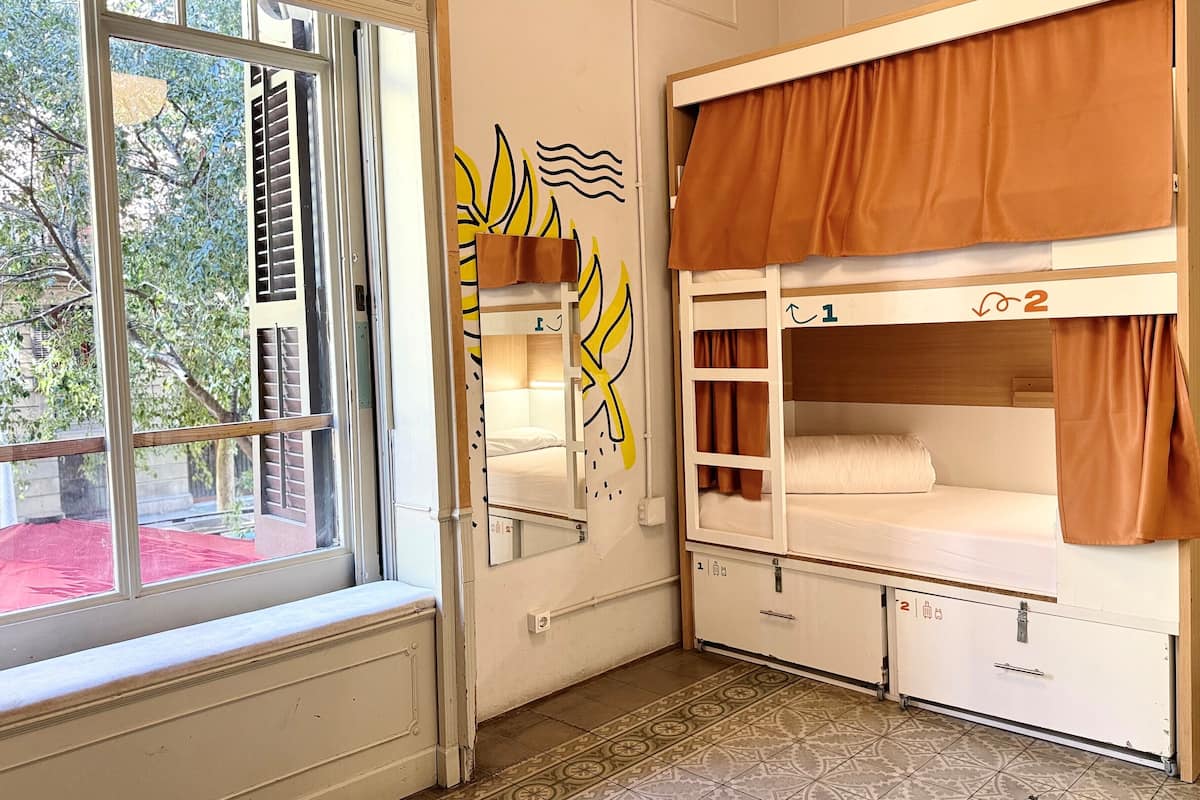 A room with bunk beds, a window, and a mirror with a leaf design.