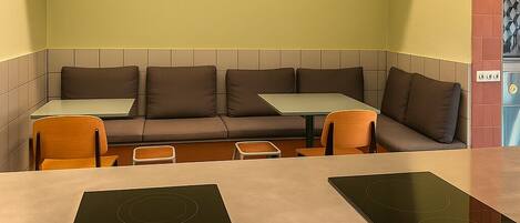 Eine Sitzecke mit einer Couch, einem kleinen Tisch und zwei Kochfeldern.