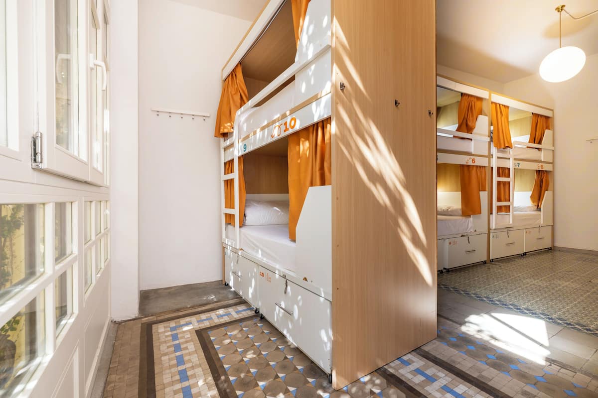 A dormitory room with bunk beds, a window, and a patterned floor.