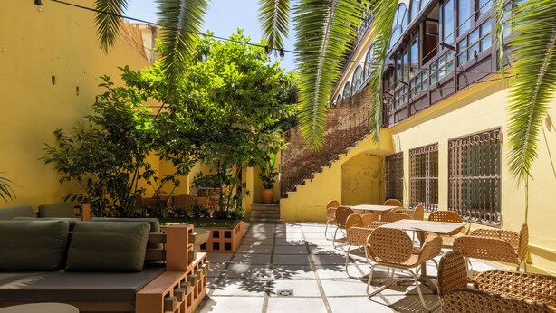 A sunlit courtyard with outdoor seating, a staircase, and lush greenery. - The Loft House Barcelona (Barcelona)