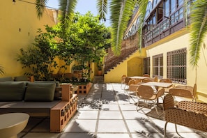 A sunlit courtyard with outdoor seating, a staircase, and lush greenery. - The Loft House Barcelona (Barcelona)