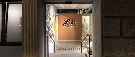 Entrada a un hostal con un letrero que dice "The Loft House" y "HOSTEL ACCESS".