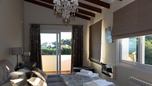 Un dormitorio con una cama grande, una araña, vistas al exterior y un ventanal.