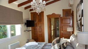 Un dormitorio con cama, candelabro, televisor y puertas de madera.