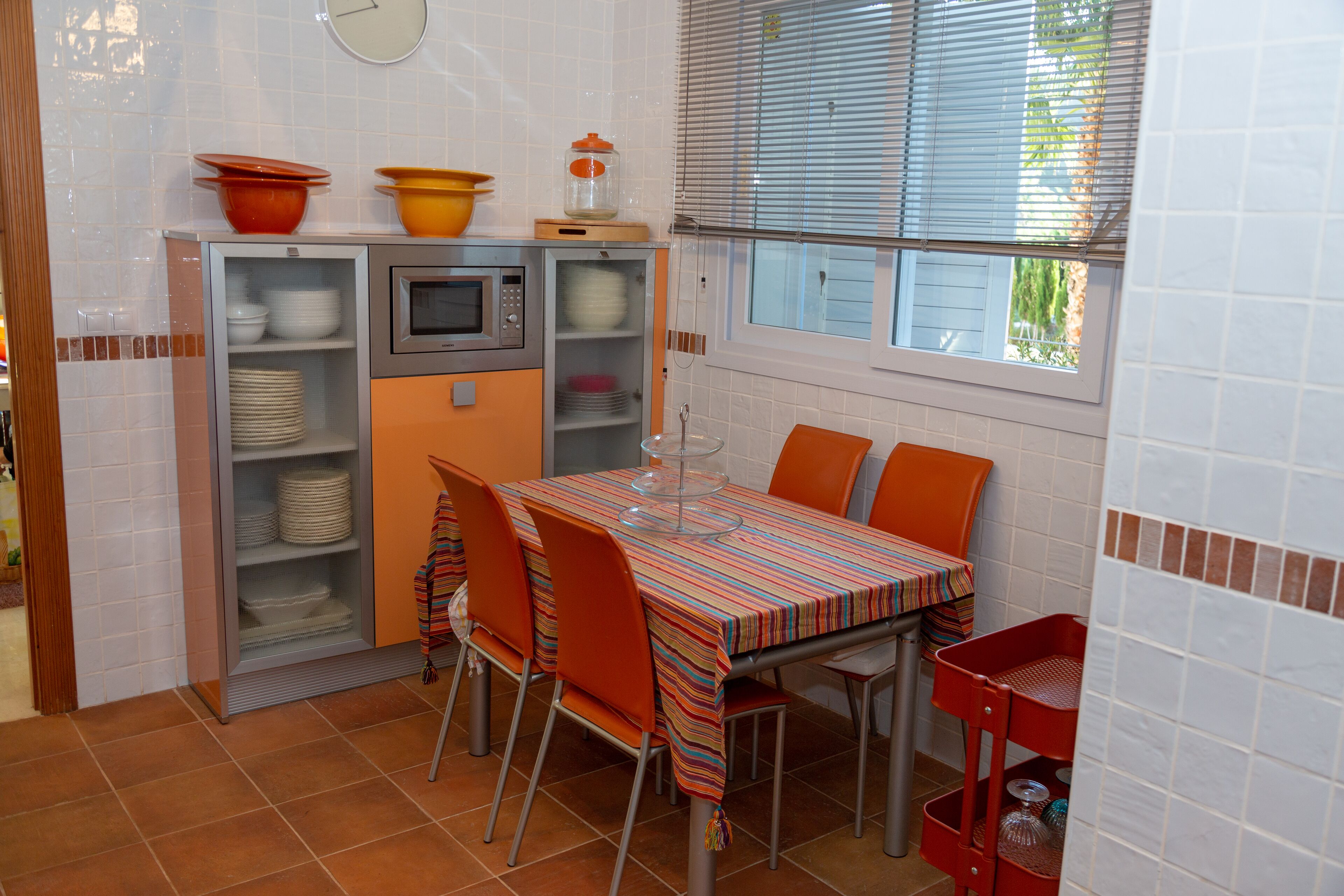 Una cocina compacta con una mesa de comedor, sillas y microondas.