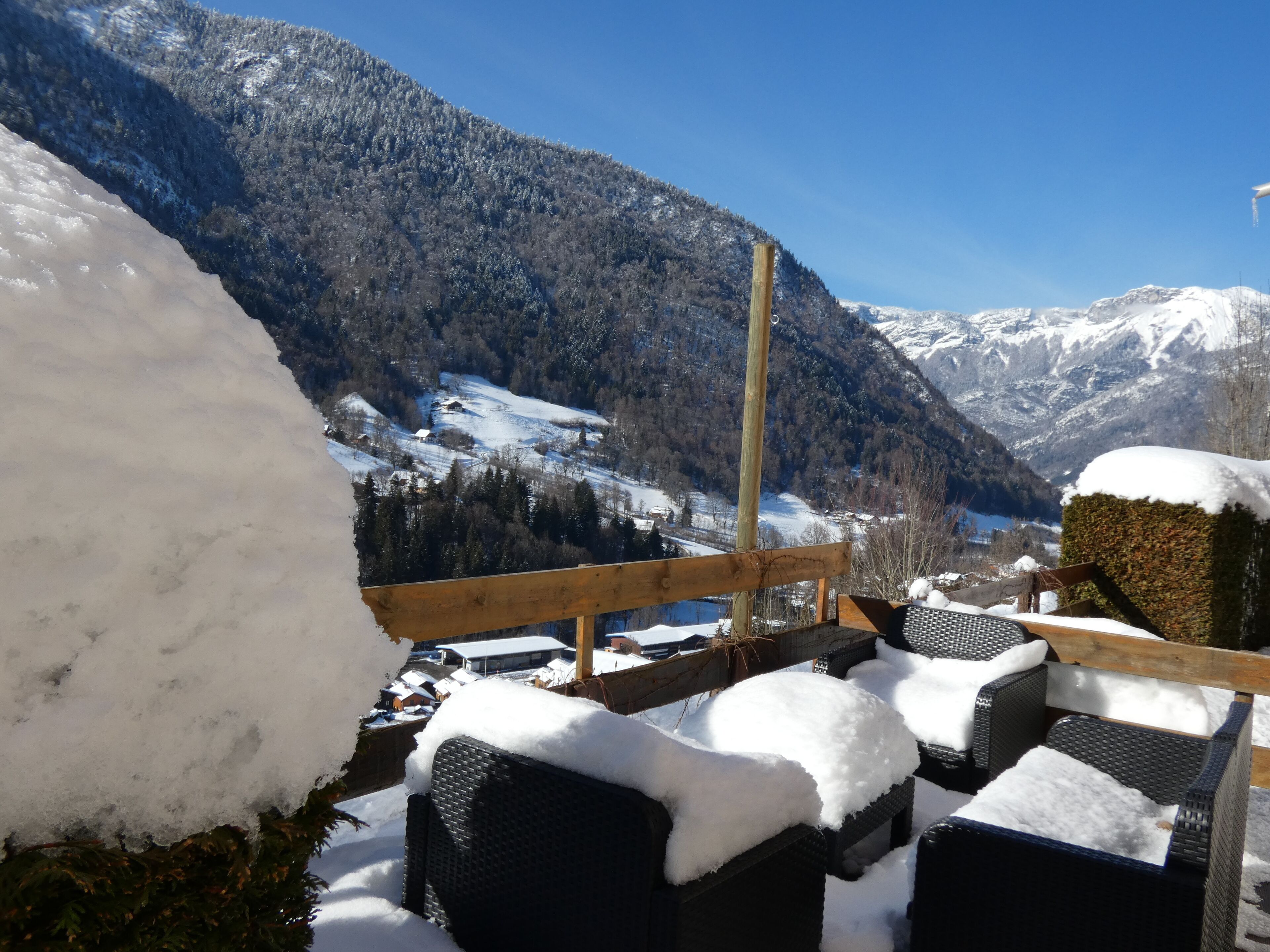 A snow-covered outdoor seating area with a view of a mountainous landscape.