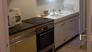 Een kleine keuken met een magnetron, koffiezetapparaat en oven.