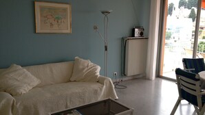 Een woonkamer met een bank, een salontafel, een vloerlamp, een radiator en een stoel.