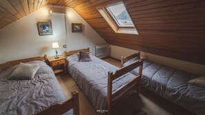 A cozy attic bedroom with two wooden beds, a skylight, and a small bedside table with a lamp. - Nice triplex with balcony and mountain view, near ski- WIFI ACCESS (Saint-Lary-Soulan)