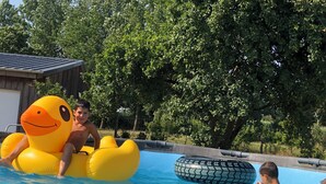 A swimming pool with inflatable toys and a wooden structure in the background.