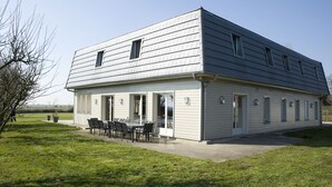 A two-story building with a flat roof, large windows, and a patio with outdoor seating.