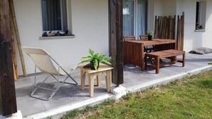 Un patio con una mesa y sillas de madera, una silla plegable y una pequeña planta en maceta.