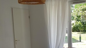 Una sala de estar moderna con una mesa de centro de vidrio, un sofá gris, un sillón marrón y una lámpara colgante de fibras naturales.