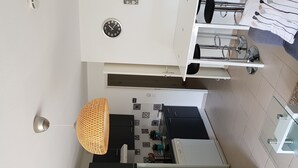 Una cocina moderna con encimera negra, armarios blancos y una lámpara colgante.