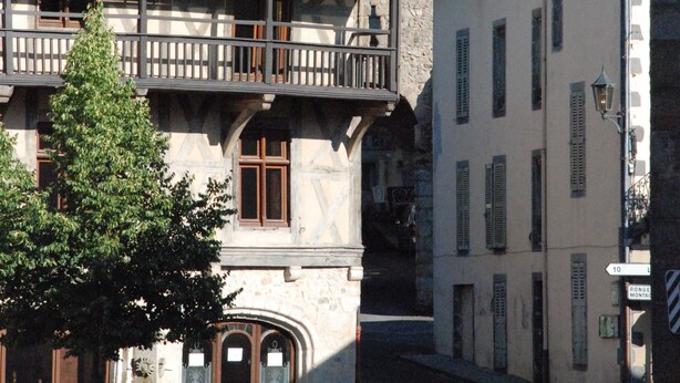 A historic building with a balcony, a clock tower, and a street with benches and trees. - Charming and comfortable loft-style gîte*** near Vichy for 4 to 5 people (Châteldon)