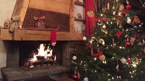 A cozy room with a fireplace, a Christmas tree, and a shelf with books and a teddy bear. - Chalet 12-14 people  Le Grand Bornand - Chinaillon  (Le Grand-Bornand)