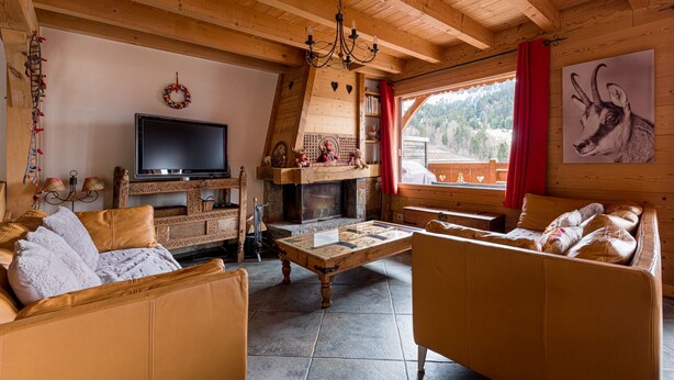 A cozy wooden cabin interior with a fireplace, a television, and a sofa. - Chalet 12-14 people  Le Grand Bornand - Chinaillon  (Le Grand-Bornand)