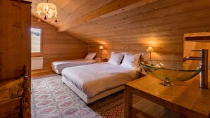 A cozy wooden cabin bedroom with two beds, a glass sink, and a patterned rug. - Chalet 12-14 people  Le Grand Bornand - Chinaillon  (Le Grand-Bornand)