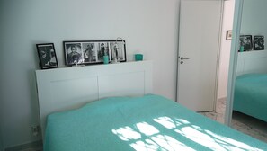 Un dormitorio con cama, cabecera blanca y pared adornada con fotos enmarcadas.