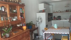 Una cocina con armarios de madera, una mesa de comedor con sillas, un microondas y un refrigerador.