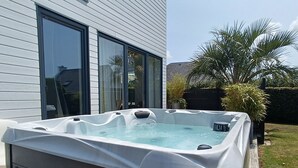 A hot tub in a backyard with a house in the background. - Bright house with garden and spa, 100 m from the beach. Pets welcome. (Plouguerneau)