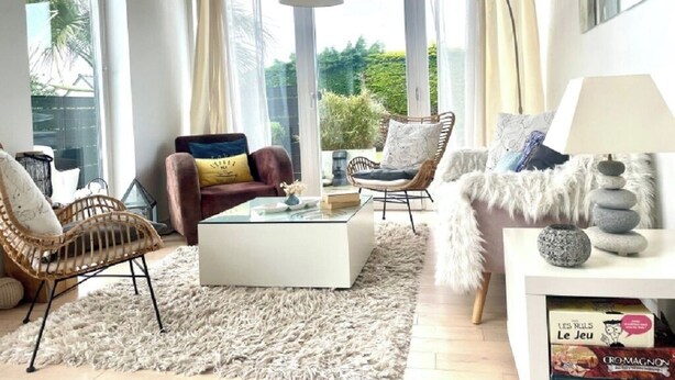 A well-lit living room with a large window, a white coffee table, and two sofas with cushions. - Bright house with garden and spa, 100 m from the beach. Pets welcome. (Plouguerneau)