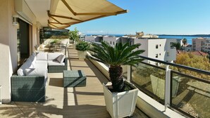 A balcony with outdoor furniture, a large umbrella, and a potted plant. - Large 4P Pointe Croisette Huge terrace Sea view Beaches Wifi Air conditioning Garage (Cannes)