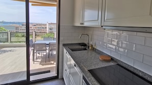 A modern kitchen with white cabinets, a granite countertop, and a large window overlooking a balcony. - Large 4P Pointe Croisette Huge terrace Sea view Beaches Wifi Air conditioning Garage (Cannes)