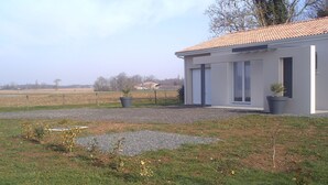Un bâtiment moderne avec un toit en tuiles, de grandes fenêtres et une allée gravillonnée.