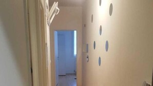 A corridor with wooden flooring and white walls, leading to a room with a door. - Rental Apartment F3 Fontenay-aux-Roses (Fontenay-aux-Roses)