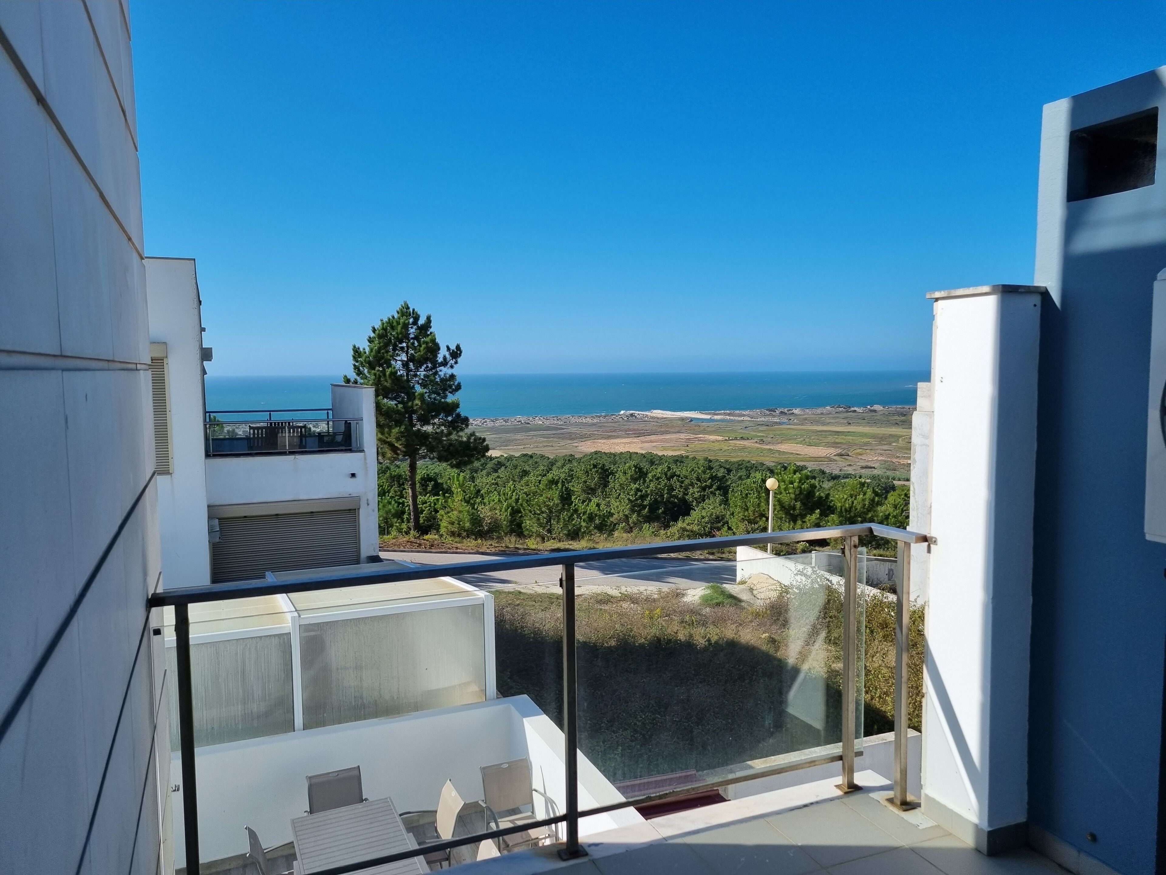 A modern balcony with a clear view of the sea and a distant landscape.