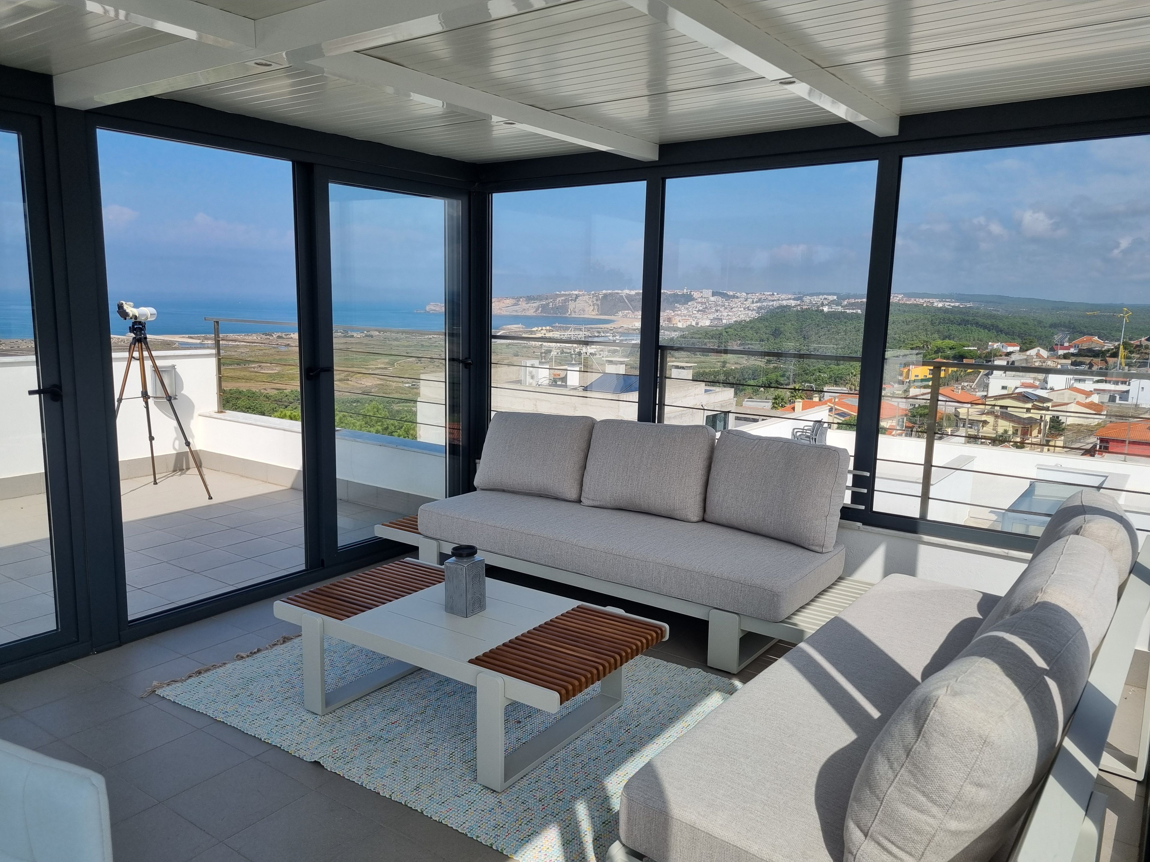 Een modern balkon met een bank, een bijzettafeltje en een telescoop.