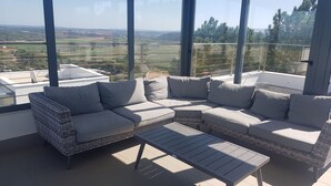 A modern outdoor seating area with a large sectional sofa and a small table, overlooking a scenic landscape. - Villa d'ARCHITECTE, Sur les hauteurs, VUE MER, calme, TERRASSE 360°.   (casal mota)