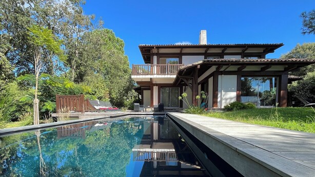 Una casa moderna con piscina, rodeada de abundante vegetación.