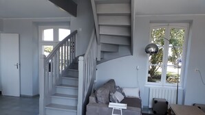 A living room with a grey sofa, a small table, and a staircase.