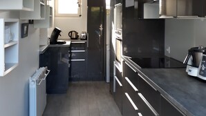 A modern kitchen with dark cabinetry, a built-in oven, and a coffee maker.