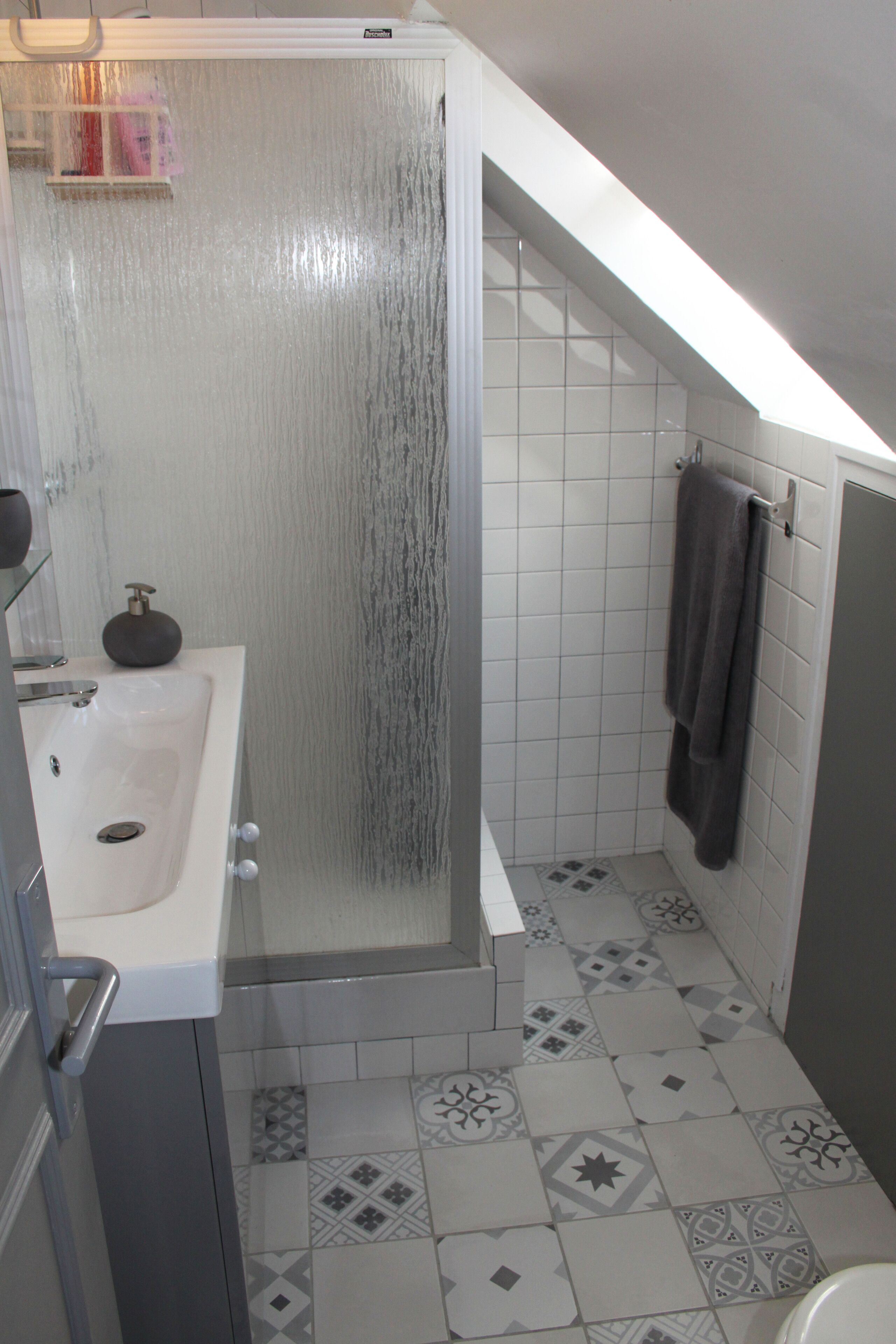 A bathroom with a shower, sink, and tiled floor.