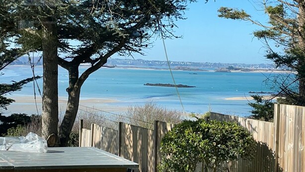 A wooden deck overlooking a beach with a clear view of the sea and distant shoreline.