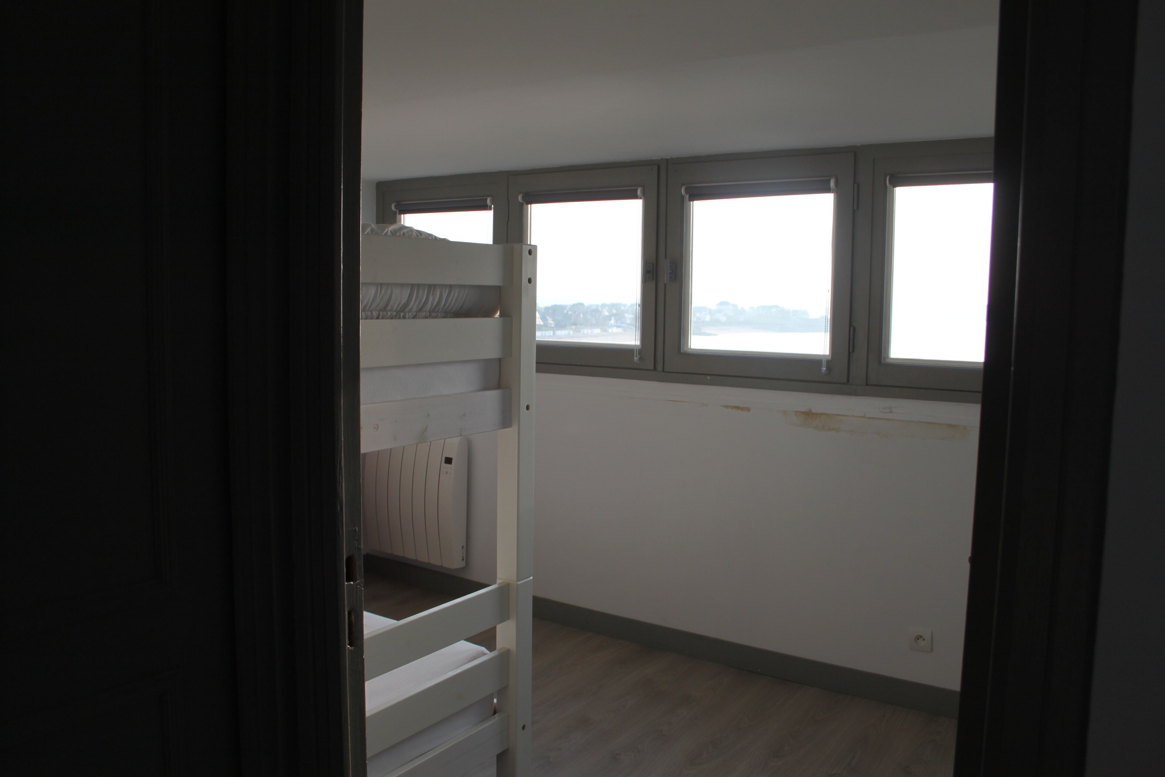 Una habitación con literas, ventanas amplias y un radiador.