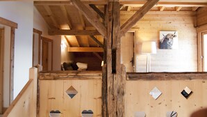 Un intérieur en bois avec un lit en mezzanine, des découpes en forme de cœur et une image de vache sur le mur.