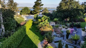 Ein gepflegter Garten mit verschiedenen Pflanzen, einem kleinen Teich und einer Terrasse mit Gartenmöbeln.