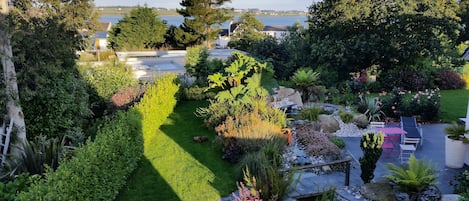 A well-maintained garden with a variety of plants, a small pond, and a patio area with outdoor furniture.