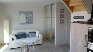 Ein modernes Wohnzimmer mit einem weißen Sofa, einem Glastisch und einem Bild an der Wand.