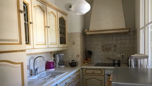 Una cocina con armarios de madera, encimera blanca, cafetera, hervidor y tostadora.