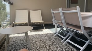 A balcony with two white chairs and a small table, patterned floor tiles, and a view of the city. - Grand T3 luxury duplex in highly sought after residence (Gruissan)