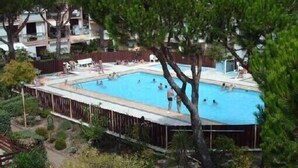 A swimming pool surrounded by a wooden deck, with people swimming and lounging. - Grand T3 luxury duplex in highly sought after residence (Gruissan)