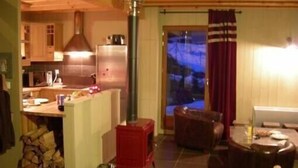 A cozy living room with a fireplace, a dining area, and a kitchen with wooden cabinets and a modern stove.