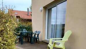 Een terras met een tafel en stoelen, een groene stoel en een schuifpui.