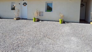 A building with a tiled roof, a gravel driveway, and three potted plants. - Cozy vacation rental in the Arcachon Basin for 2–3 people: peaceful setting, amenities, and beaches (Gujan-Mestras)