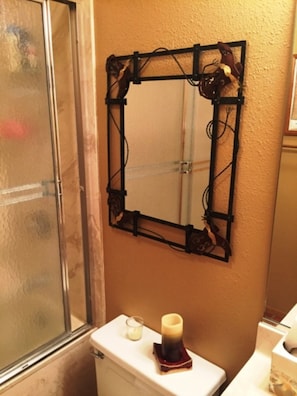 A bathroom with a shower enclosure, a toilet, and a wall-mounted mirror with a decorative frame. - Cedars 9 (Angel Fire)